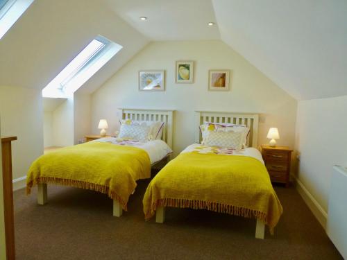 sypialnia z 2 łóżkami i żółtymi kocami w obiekcie Cairndoon Byre w mieście Monreith