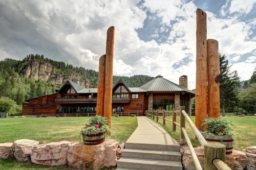 a log cabin with a path leading to a building at Spearfish Canyon Lodge in Spearfish