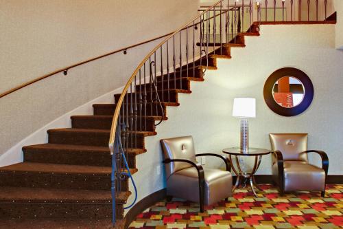 a lobby with a staircase with two chairs and a table at Baymont by Wyndham Harrisburg in Harrisburg