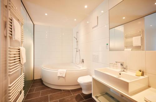 a white bathroom with a tub and a toilet and a sink at Vital Hotel an der Therme GmbH in Bad Windsheim