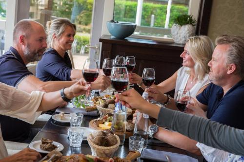 a group of people sitting around a table drinking wine at Strandhotel Bos en Duin in Oostkapelle