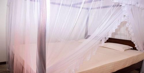 a white canopy bed with white curtains in a room at Seals Harbor Hotel in Weligama