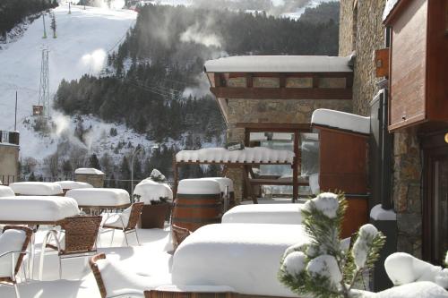 a snowy patio with tables and chairs in the snow at Hôtel Bruxelles in Soldeu