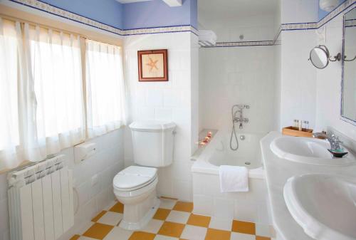 y baño con aseo, bañera y lavamanos. en Casona de La Paca, en Cudillero