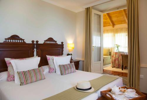 1 dormitorio con 1 cama blanca grande con sombrero en Casona de La Paca, en Cudillero