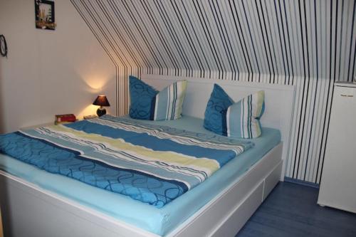 a bed with a blue comforter and pillows at Großes, einzeln stehendes Ferienhaus "Undine", ruhige Lage, Terrasse, Parkplatz, Fahrradhäuschen abschließbar, Nähe zur Altstadt und 600 m zum Müritz - Strand in Waren