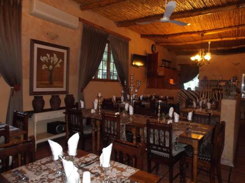 a dining room with tables and chairs and a ceiling at Old Mill Lodge, Seasonal Working Ostrich Farm & Restaurant, Oudtshoorn in Oudtshoorn