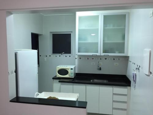 a white kitchen with a sink and a refrigerator at Apartamento Praia in Guarujá