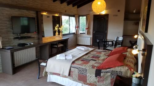 um quarto com uma cama e uma televisão num quarto em Aires Serranos - Suites em La Cumbrecita