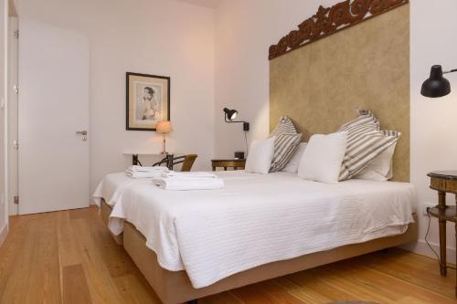 a bedroom with a large bed with white sheets at Center Gardens Apartments in Lisbon