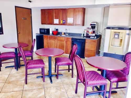 a kitchen with two tables and pink chairs and a kitchen at Lyons Inn in Lyons
