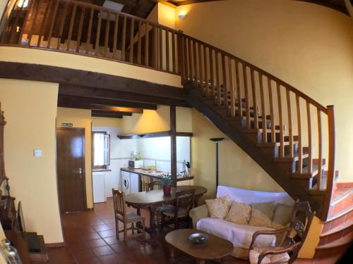 a living room with a staircase with a couch and a table at El Bulin de Horcajuelo in Horcajuelo de la Sierra