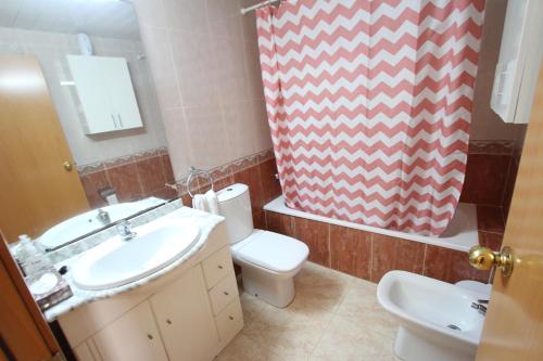 a bathroom with a sink and a toilet and a mirror at Apartamento Cap de Salou in Salou