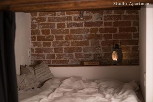 a bed in a room with a brick wall at "Schwarzer Speicher" Stralsund in Stralsund