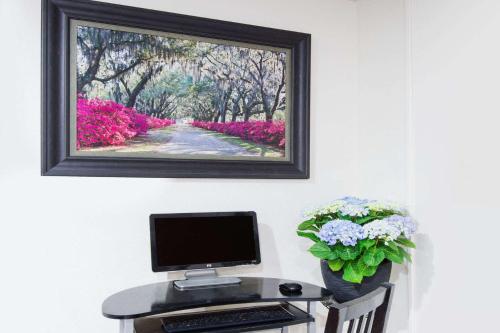a computer on a desk with a picture on the wall at Super 8 by Wyndham Pittsburgh PA Airport-University Area in Moon Township