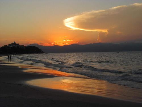 a sunset on the beach with the sun setting at Apart Hotel Beira do Mar in Florianópolis