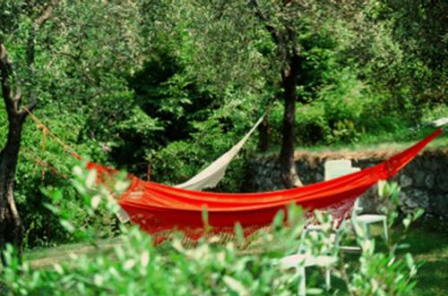 a red hammock in a garden with trees at Hotel Oasi Beach in Malcesine