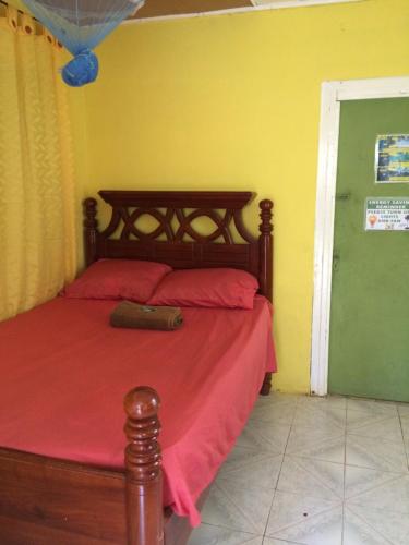 a bedroom with a bed with a red comforter at T&T - Tatty and Tony Guesthouse in Negril