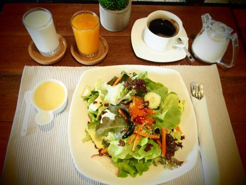 a plate of salad and a cup of coffee on a table at Chernchan Hostel in Chanthaburi