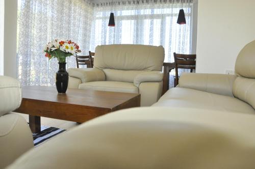 a living room with two chairs and a table with flowers at Forest View Lodge in Nuwara Eliya