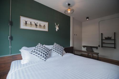 a bedroom with a white bed and a green wall at Chernchan Hostel in Chanthaburi