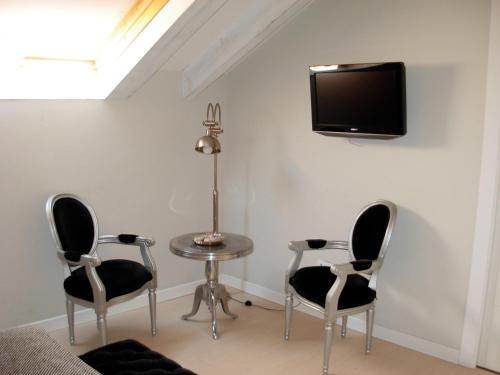 a room with two chairs and a table and a tv on the wall at Hotel el Jardín de Eugenia in Ribadesella