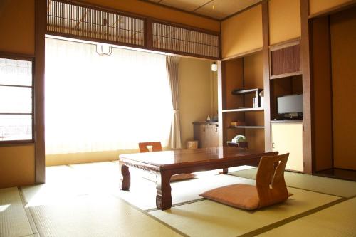 uma sala de estar com uma mesa de madeira e cadeiras em Nakaya Ryokan em Minakami