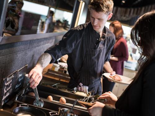a man preparing food in a kitchen with a woman at Weinlodge Siedler in Mautern