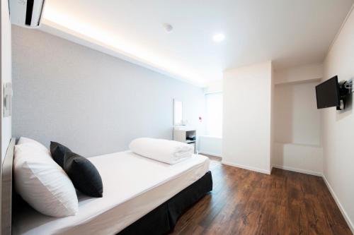 a bedroom with a bed with white sheets and pillows at Seoul Grand Hostel EWHA Univ in Seoul
