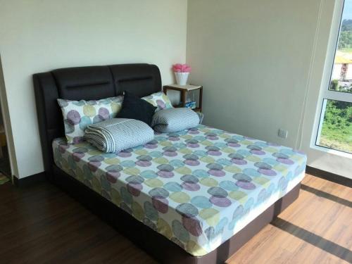 a bed with two pillows on it in a room at Sandakan Spacious and Comfortable Pool View Condo in Sandakan
