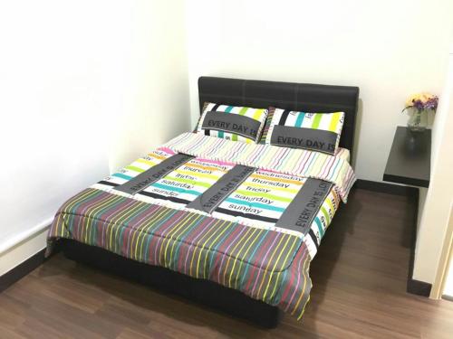 a bed with a multicolored comforter and pillows at Sandakan Spacious and Comfortable Pool View Condo in Sandakan