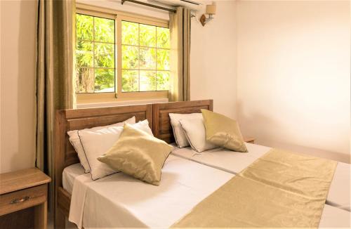 - une chambre avec un lit avec deux oreillers et une fenêtre dans l'établissement Korrine's Cottage HORIZON, à Beau Vallon