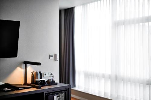 a room with a window and a table with a lamp at Arban City Hotel in Busan