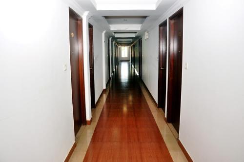 a long hallway with white walls and a wooden floor at Emporium Hotel in Mangalore