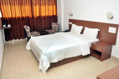 a bedroom with a large bed with a wooden headboard at Emporium Hotel in Mangalore