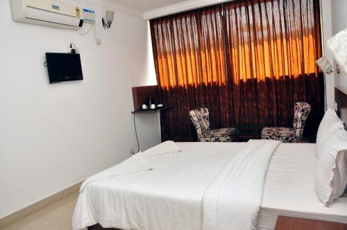 a bedroom with a bed and two chairs and a window at Emporium Hotel in Mangalore