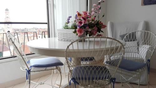 a table with chairs and a table with flowers on it at Appartamento Bellavista con parking privato, a un passo dal Teatro Ariston in Sanremo