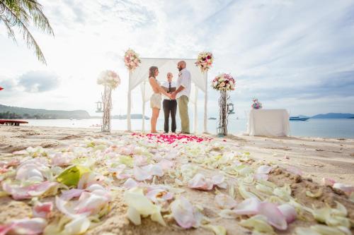 a bride and groom standing on a beach at Secret Garden Beach Resort in Bangrak Beach