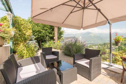 a patio with a table and chairs and an umbrella at Auberge Le Cabaliros in Argelès-Gazost