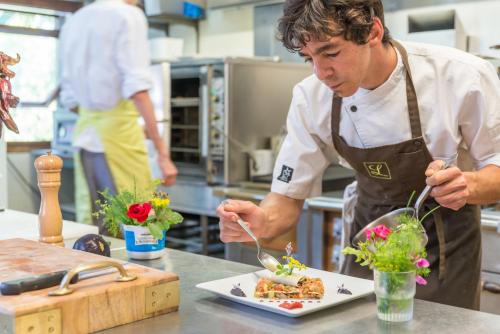 Un homme dans une cuisine préparant une assiette de nourriture dans l'établissement Auberge Le Cabaliros, à Argelès-Gazost