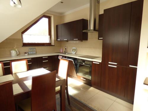 a kitchen with wooden cabinets and a table with a dining room at Dolina Leśnicy SKI & SPA Resort in Brenna