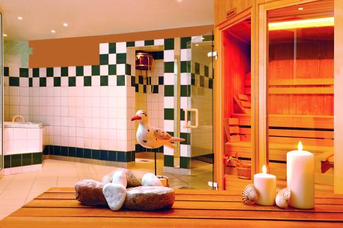 uma casa de banho com velas e um pato no chuveiro em Sonnenresort Hüttmann em Norddorf