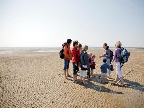 a group of people standing on the beach at Hotel Hüttmann in Norddorf