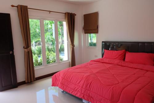 a bedroom with a red bed and a window at Maikhao Beach Guest House in Mai Khao Beach