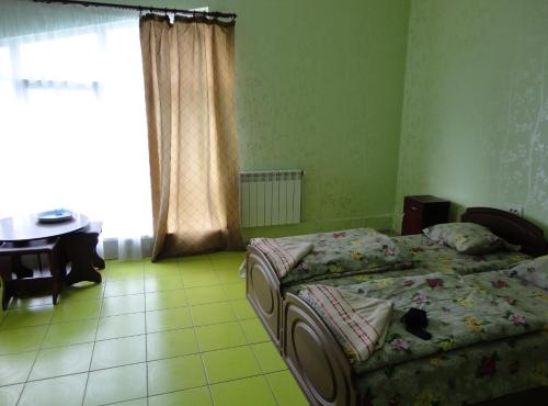 a bedroom with two beds and a table and a window at 4 Seasons in Boryspilʼ