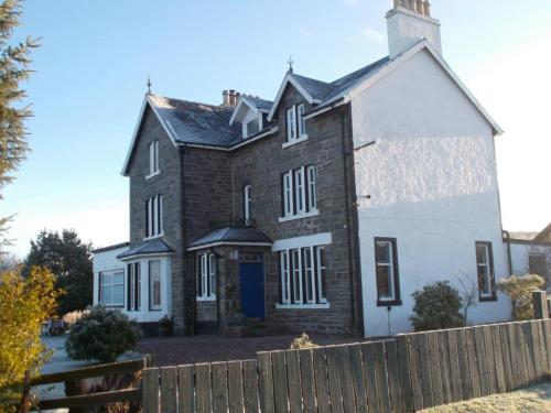 a large brick house with a fence in front of it at Loch Shiel Hotel in Acharacle