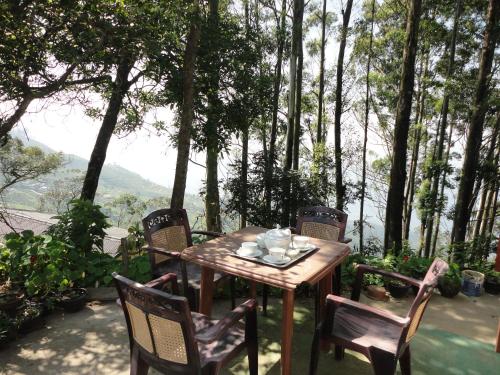 a wooden table and chairs on a patio with trees at Bel View Guest House in Haputale