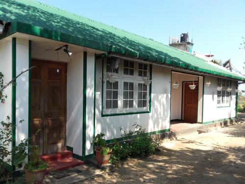a white and green house with a green roof at Bel View Guest House in Haputale