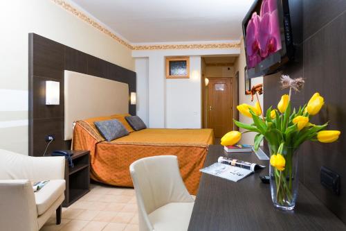 a hotel room with a bed and a table with flowers at Taki Village in Brenzone sul Garda