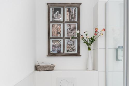 a bathroom with a vase of flowers and a picture at Boutique Apartments Kirchzarten in Kirchzarten